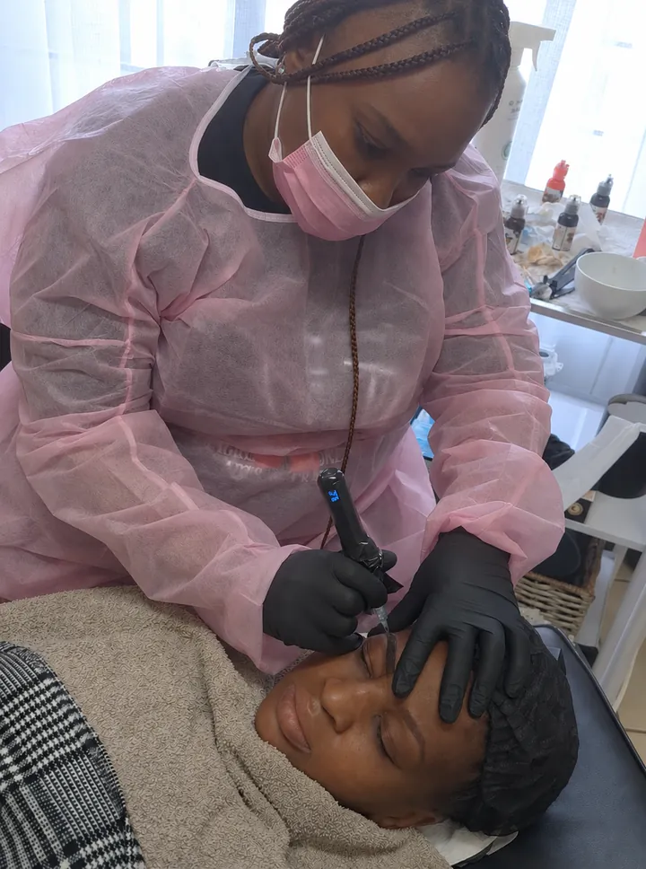 PMU student doing brows on a model during training with Tess